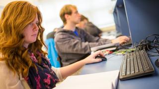 一个红头发的女学生坐在电脑前输入信息.